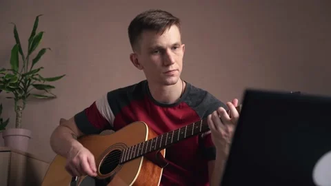 Young man is learn.ing to play the acoustic guitar. online learning. Stock Footage 211813207