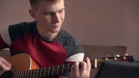 Young man learning to play acoustic guitar online at home. close-up. Stock Footage 212612968