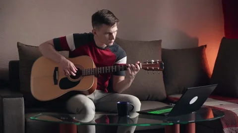 Young man is learn.ing to play the acoustic guitar. online learning. Stock Footage 212613441