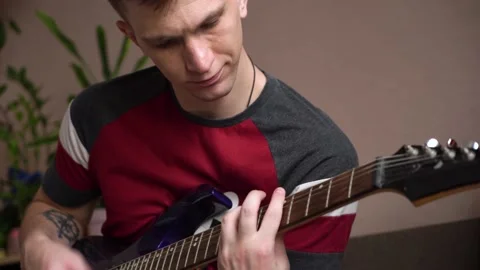 Young man is learning to play the electric guitar online using a laptop. Stock Footage 209307352