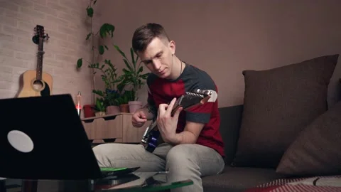 Young man learning to play electric guitar online at home. Stock Footage 209307661