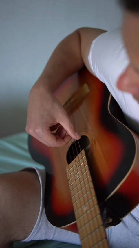 Young man is learning to play the guitar at home, a cat is lying next to hi.. Stock-Footage 276379458