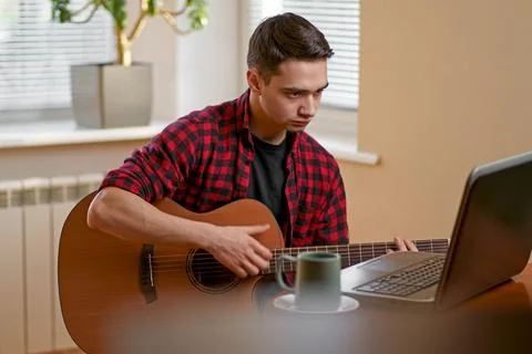 Young man learning to play guitar online Stock Photos