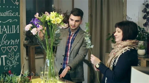 The young man is learning from a professional florist haw to work with flowers. Stock Footage 61490153