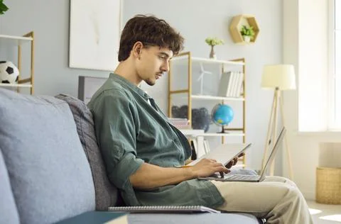 Young Man Learning Programming Online with Laptop Computer on Sofa at Home Stock Photos