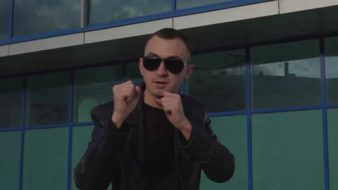 Young man in leather jacket and sunglasses standing in combat pose outdoor Stock Footage 97879948