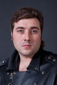 Young man in a leather jacket on a gray background Stock Photos