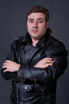 Young man in a leather jacket on a gray background Stock Photos