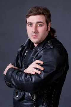 Young man in a leather jacket on a gray background shot in studio Stock Photos