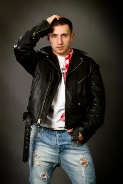 Young man in a leather jacket on a gray background Stock Photos