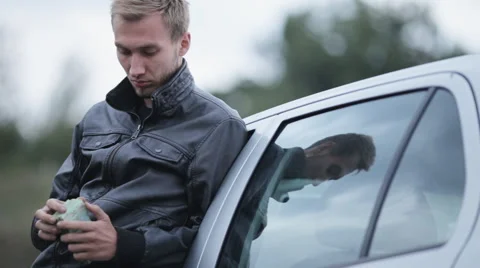 A young man in a leather jacket holding money near the car Stock Footage 55334984