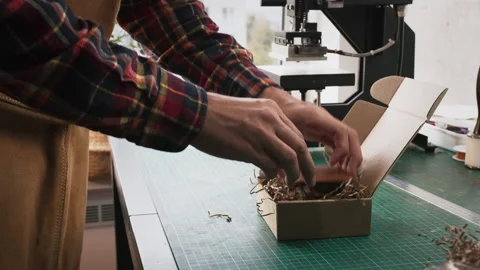 Young man leather maker packing in small cardboard box leather handmade wallet Stock Footage 140520266