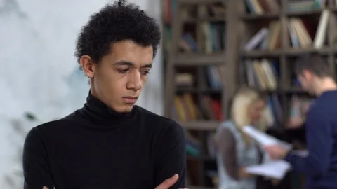 Young man in library loking back on couple serious Stock Footage 121539145