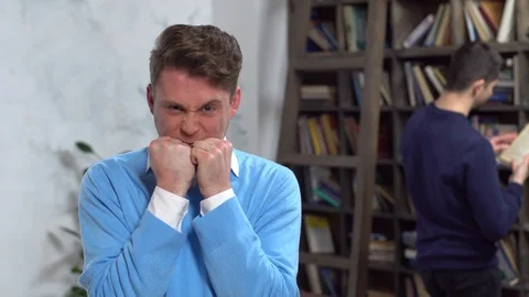 Young man in library looking camera smiling biting fists Stock Footage 121646959