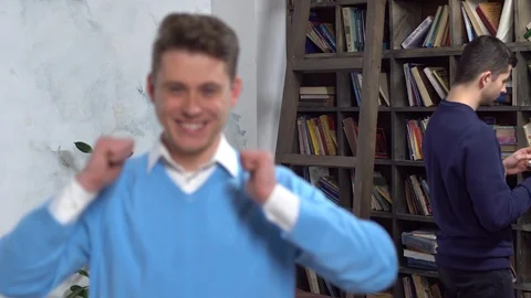 Young man in library showing thumbs up blurred guy at back looking at him Stock Footage 121477821