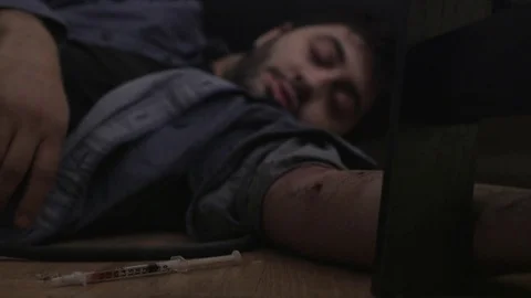 Young man lies unconscious by needle after overdose Stock Footage