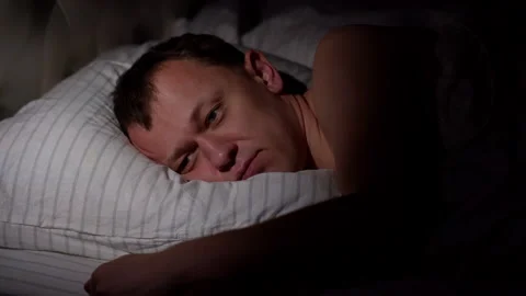 A young man lies without sleep, cannot fall asleep, whips a pillow Stock Footage 134479055