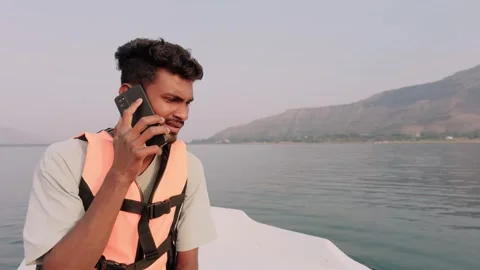 Young Man in life jacket talking on phone alone seated on speed boat with w.. Stock Footage 263953908