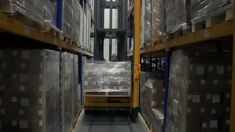 Young man is lifting cargo using forklift in industrial warehouse during working Stock Footage 124453676