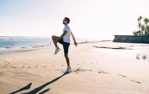 Young man lifting knee while having workout Stock Photos