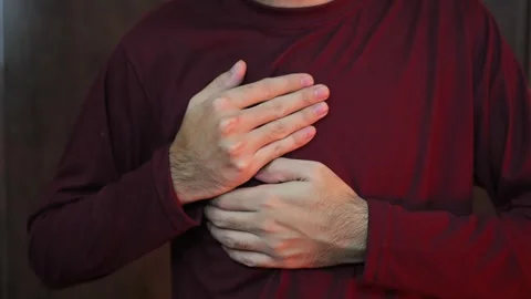 A young man in a light shirt experiences pain in the heart due to severe str 库存影片 337847245