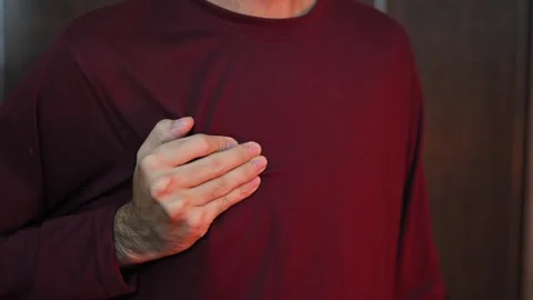 A young man in a light shirt experiences pain in the heart due to severe str 動画素材 337847254