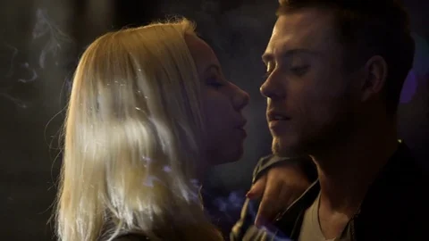 man lighting woman's cigarette Young man lighting woman's cigarette in nightclub, drunk couple kissing