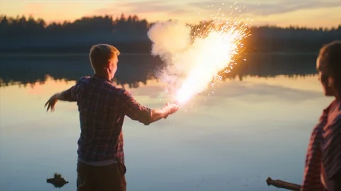 Young man lights color fire at sunset Stock Footage 98947039