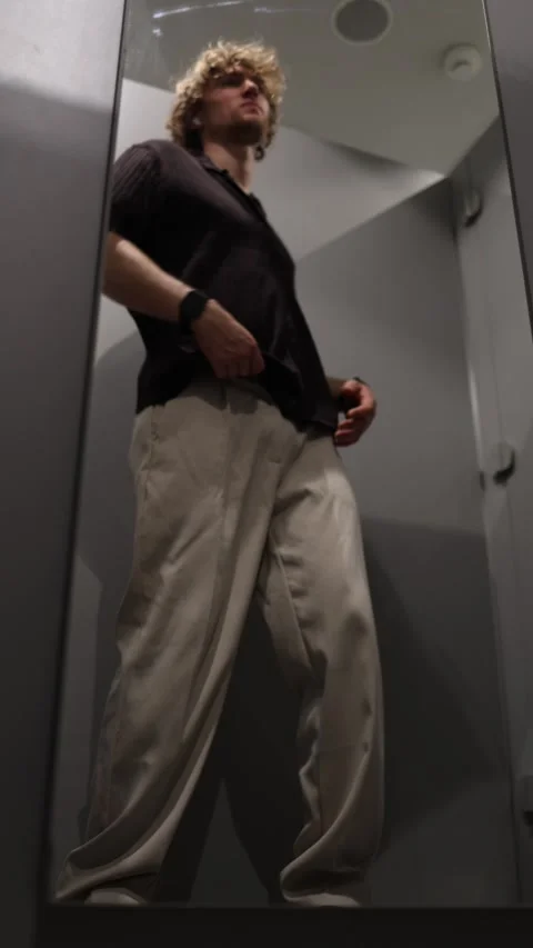 Young man likes how he looks in a T shirt while checking himself in the mirror Stock Footage 344854736