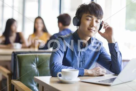 Young Man Listening To Music In Café