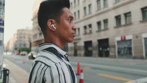 Young man listening to music while standing on crosswalk 스톡 동영상 227101538