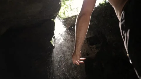 Young man liting hand towards sun in wonderful hidden waterfall spot, Stock-Footage 136502964
