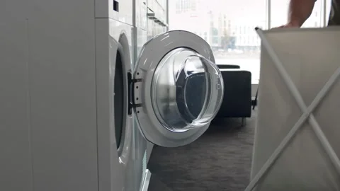 Young Man Loading Clothes Into Washing Machine In Kitchen Video stock 137329096