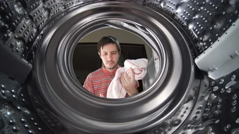 Young man is loading laundry in washing machine. View from inside. Stock Footage 149708437