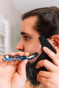Young man with a long beard, shaving with a safety razor Stock Photos