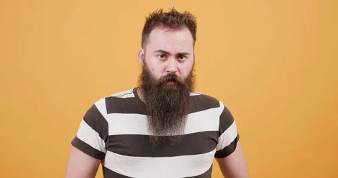 Young man with a long black beard looking serious at the camera Stock Footage 104052957