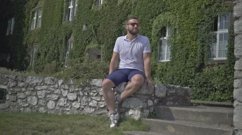 Young man looking around, sitting on the wall. Vídeo Stock 65523384