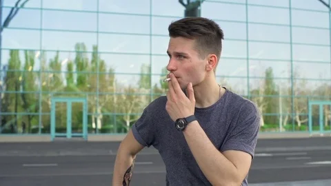Young man looking away and smoking a cigarette slow motion Stock Footage 75695966