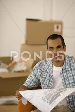 Young man looking at blueprints in new house Stock Photos