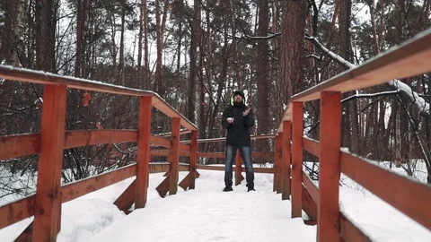 A young man looking at the camera and playing with snow in winter forest. It Stock Footage 73669637