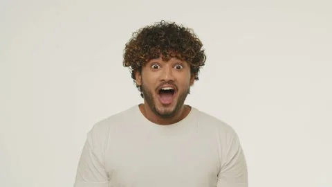 Young man looking at camera and opening mouth in amazement. Front view of Stock Footage 232227984