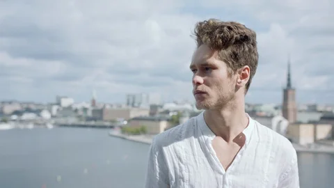 A young man looking into the camera on a hill in Stockholm. Vidéo 116083793