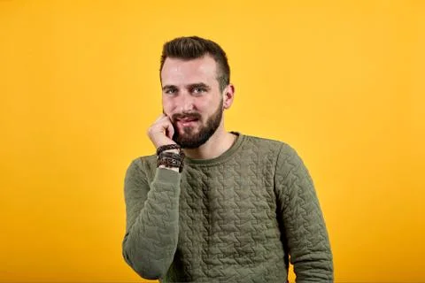 Young man looking at camera, keeping hand on chin, pretty Stock Photos