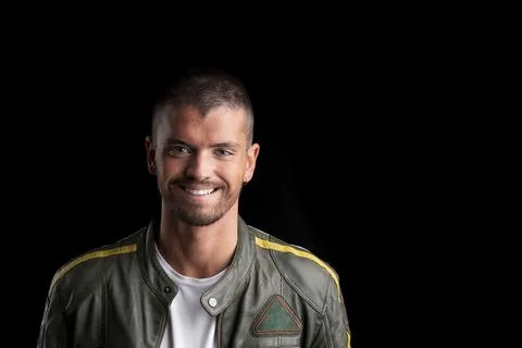 Young man looking at the camera smiling on a black background. Stock Photos