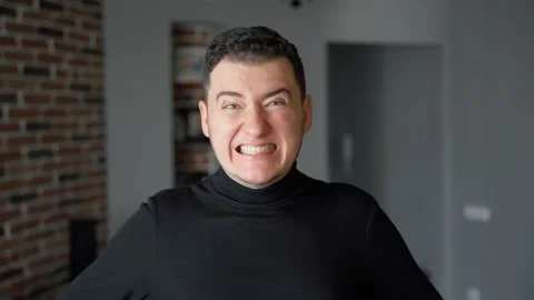 The young man is looking at the camera. Then he suddenly starts to grimace Stock Footage 151600605