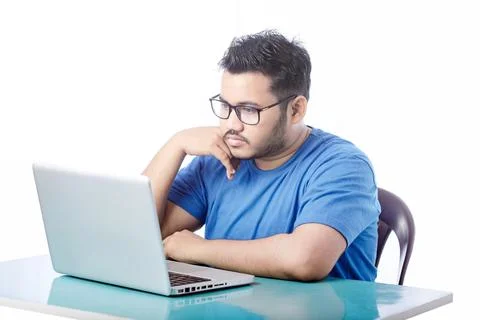 Young man looking at computer screen with blank expression putting hand under th 스톡 사진