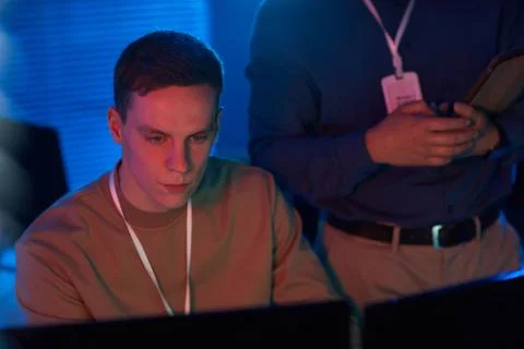 Young man looking at computer screen in data security center Stock Photos