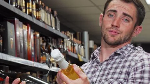 Young man looking confused while choosing wine Stock Photos