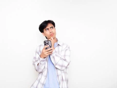 Young man looking confused while checking his smartphone, expressing doubt .. Stock Photos