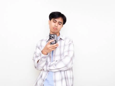 Young man looking confused while checking his smartphone, expressing doubt .. Stock Photos